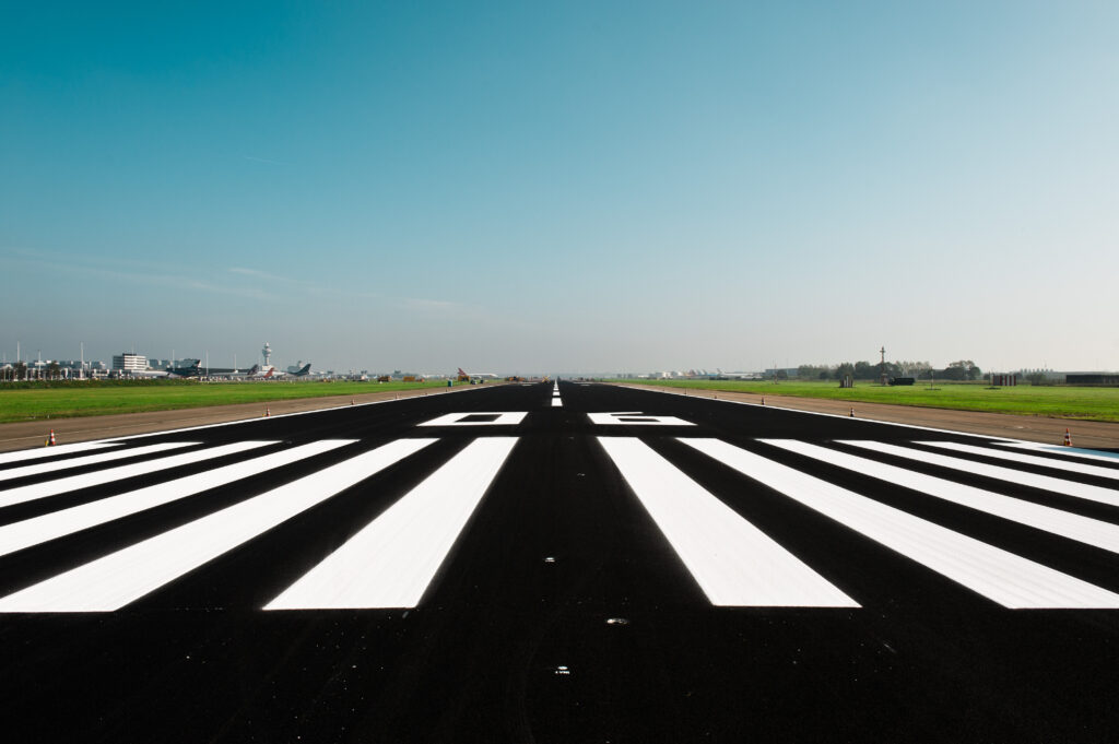 Start- en landingsbaan van een luchthaven met markering 06, gezien vanuit centraal perspectief.